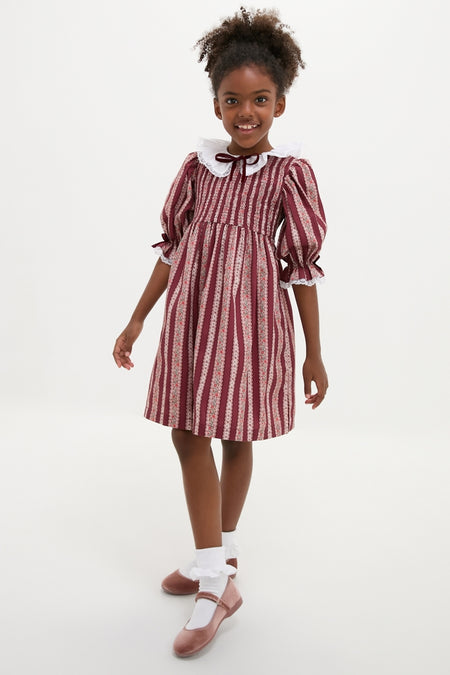 Young girl in a classic, high-end Burgundy Floral Stripe Festa Dress with effortless charm, featuring puffed sleeves, ruffled collar, and fun, swishy skirt.