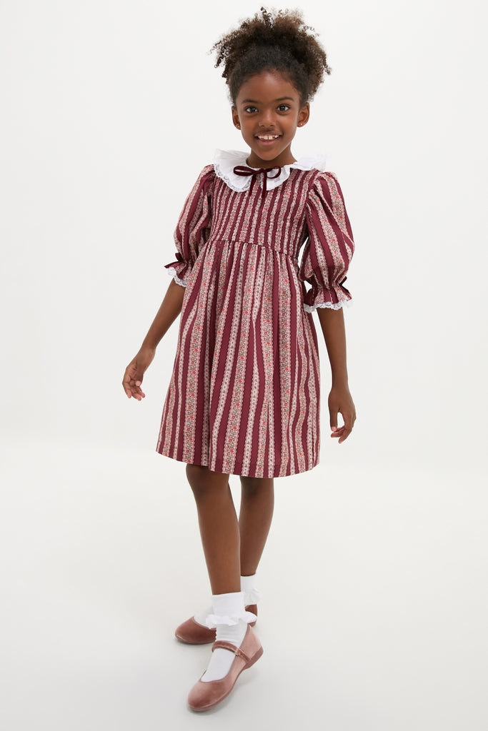 Young girl in a classic, high-end Burgundy Floral Stripe Festa Dress with effortless charm, featuring puffed sleeves, ruffled collar, and fun, swishy skirt.