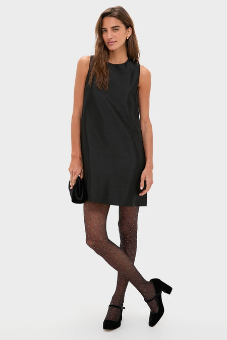 Woman in a sleeveless black mini-dress, showcasing Black and Red Multicolored Dot Tights. She completes her classic, effortless look with Mary Jane heels and a clutch.