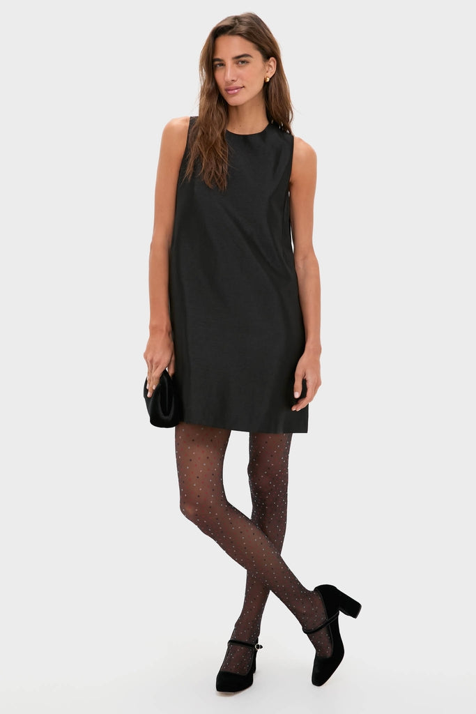 Woman in a sleeveless black mini-dress, showcasing Black and Red Multicolored Dot Tights. She completes her classic, effortless look with Mary Jane heels and a clutch.