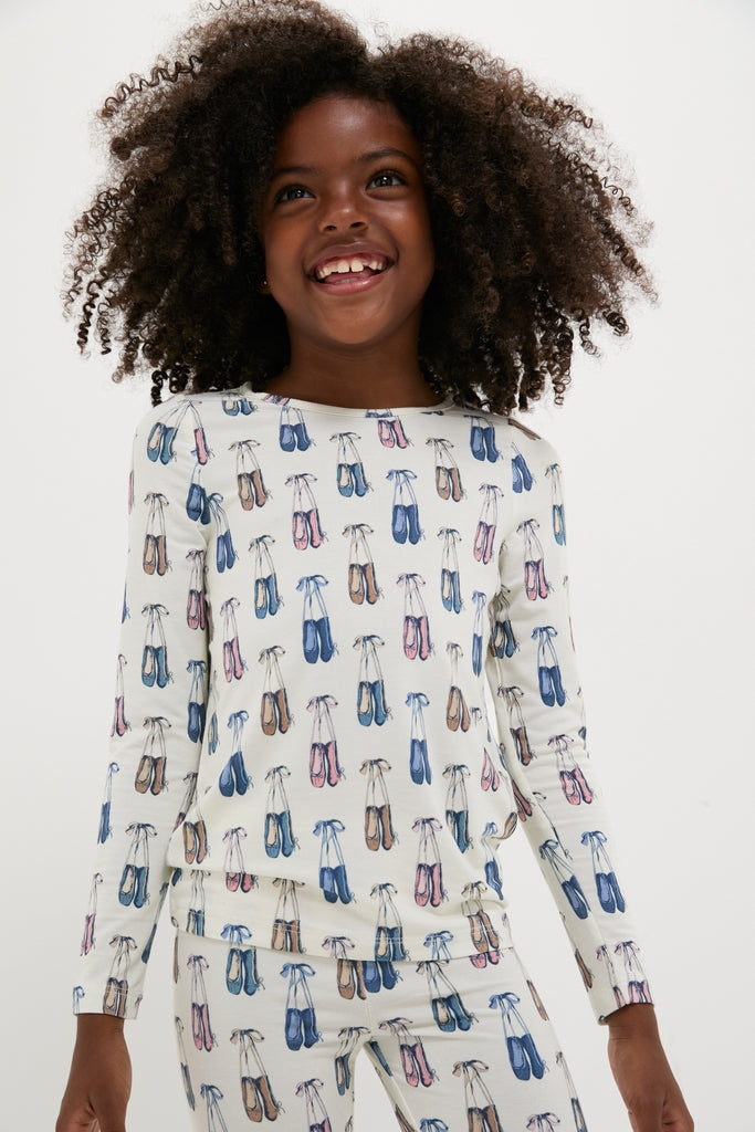 Young girl in Ballet Slippers Kids Bamboo Pj Set, smiling in classic, effortless style. The fun, high-end pajamas feature ballet slipper prints, perfect for cozy nights.