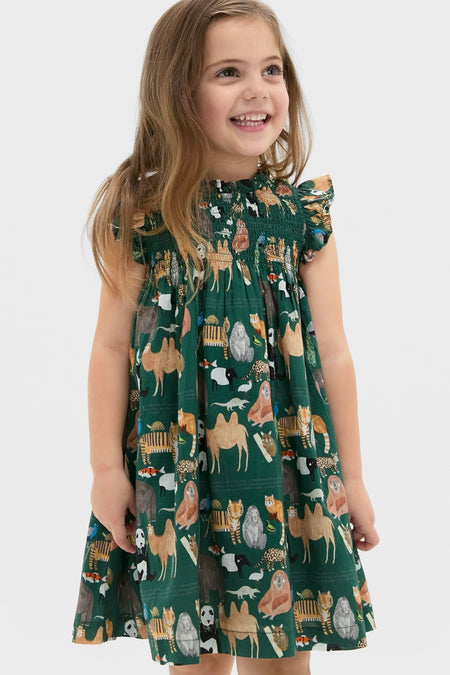 Young girl in a classic, smocked Girls Stevie Dress featuring playful animal illustrations, embodying effortless style and fun, high-end fashion.
