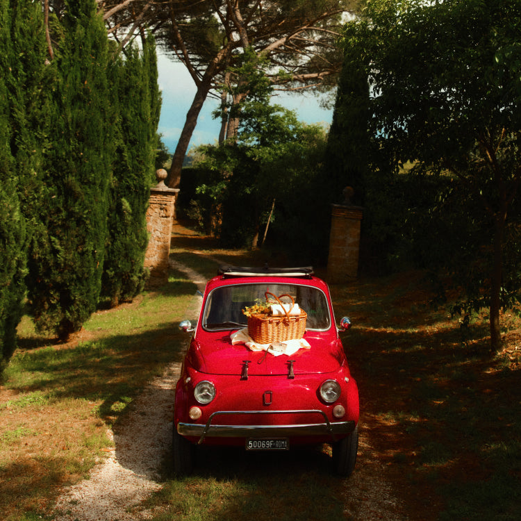 A red car with a picnic basket on the hood. 