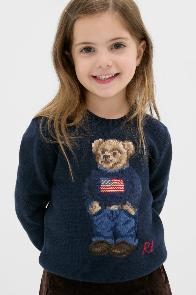 Young girl wearing the Boys Long-Sleeve Flag Bear Crewneck Sweater, featuring a classic Polo Bear in an effortlessly fun, high-end design by Ralph Lauren.