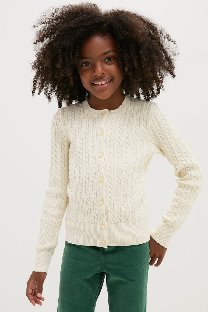 Young girl in a classic, effortless Girls Long-Sleeve Cotton Cable Knit Lurex Cardigan, smiling slightly, embodying Polo Ralph Lauren's high-end, fun style with ribbed hems and signature details.
