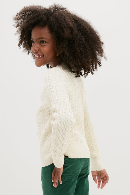 Young girl models the Girls Long-Sleeve Cotton Cable Knit Lurex Cardigan, showcasing its classic, effortless style with a fun, high-end appeal.