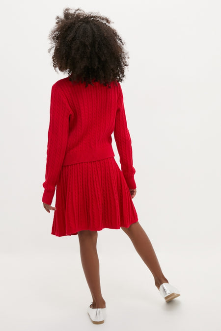 Rear view of child in Long-Sleeve Cotton Mini Cable Knit Cardigan with Matching Skirt, embodying classic, effortless style; features ribbed finishes and metallic-silver slip-on shoes.