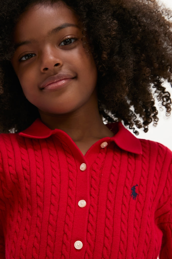 Young girl in an effortlessly classic, fun Long-Sleeve Cotton Mini Cable Knit Cardigan with Matching Skirt by Polo Ralph Lauren, embodying high-end style.