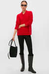 Woman models the Martin Red Cassie V-Neck Cashmere Sweater, embodying classic, effortless style with black leggings, knee-high boots, and chic accessories for a high-end, fun look.