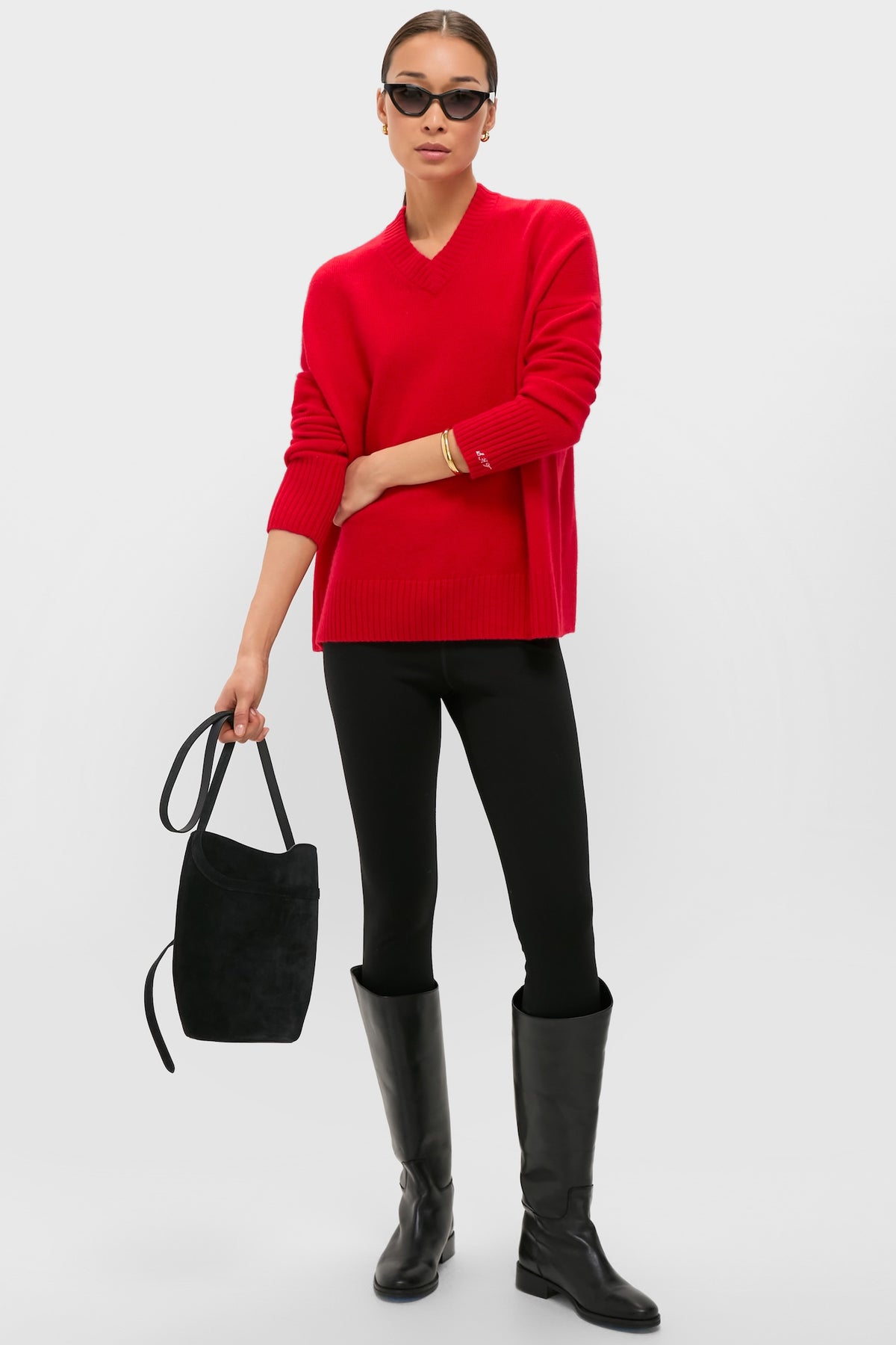 Woman models the Martin Red Cassie V-Neck Cashmere Sweater, embodying classic, effortless style with black leggings, knee-high boots, and chic accessories for a high-end, fun look.