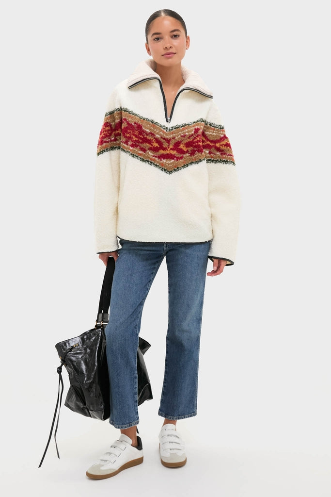 Woman in Ecru Marner Pullover with mottled red V-band, paired with classic blue jeans, carrying a slouchy tote. Effortlessly cool and high-end casual style.