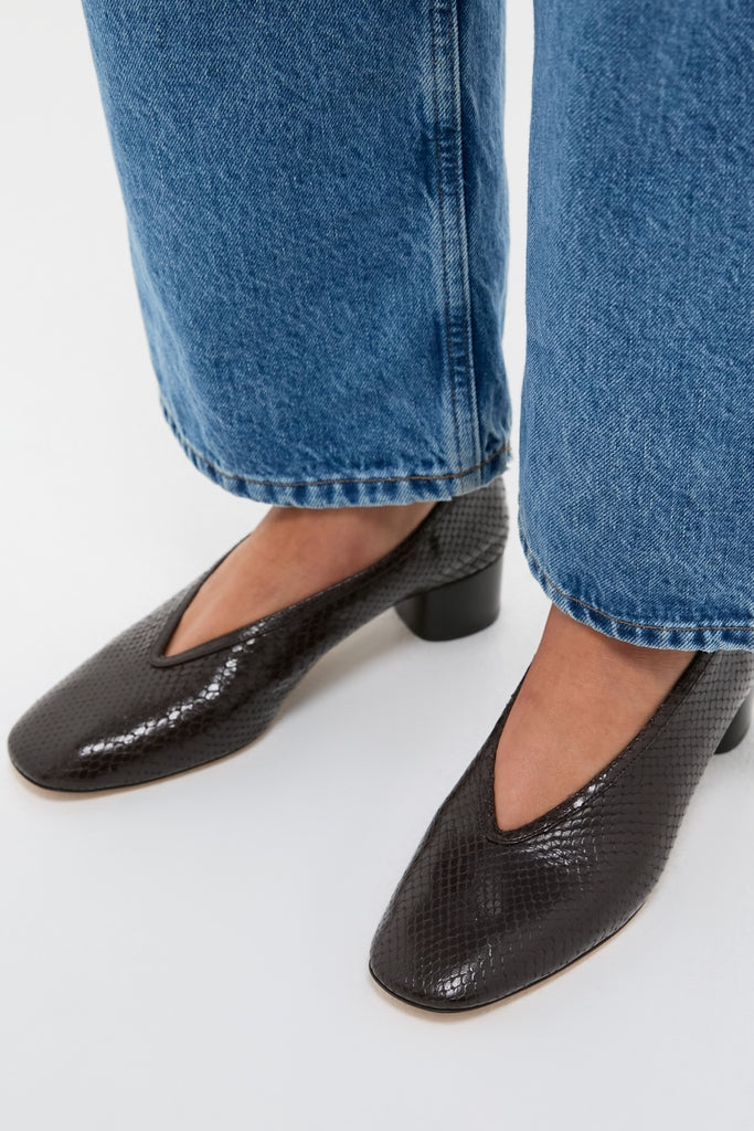 Classic, effortless style: Printed Python Luna Pumps in black leather, featuring a low block heel and V-shaped topline, paired with cropped denim jeans for a fun, high-end look.