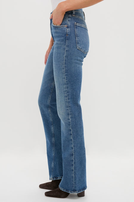 Curve Mid Rise Kick Boot jeans in medium-wash denim, featuring a classic, effortless bootcut silhouette. Paired with dark ankle boots for a fun, high-end look.