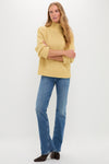 Person wearing the Curve Mid Rise Kick Boot jeans, showcasing a classic, effortless style with a subtle kick flare, paired with a chunky knit sweater and ankle boots.