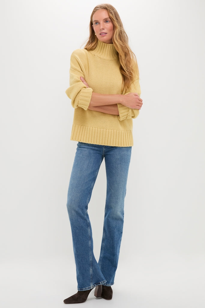 Person wearing the Curve Mid Rise Kick Boot jeans, showcasing a classic, effortless style with a subtle kick flare, paired with a chunky knit sweater and ankle boots.
