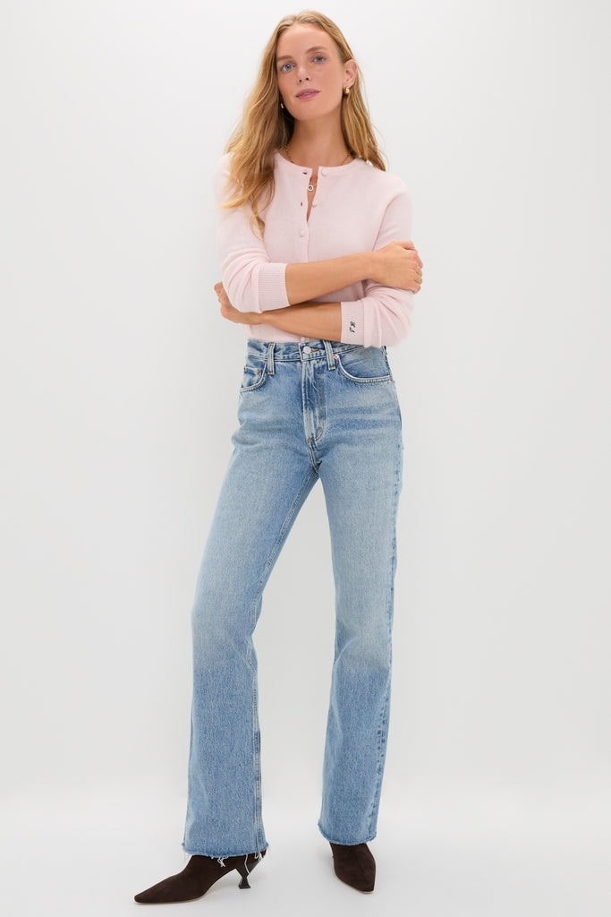 Young woman in high-rise Stage Leena Jean with classic straight leg and undone hem, styled effortlessly with a light pink sweater and heeled boots for a fun, high-end look.