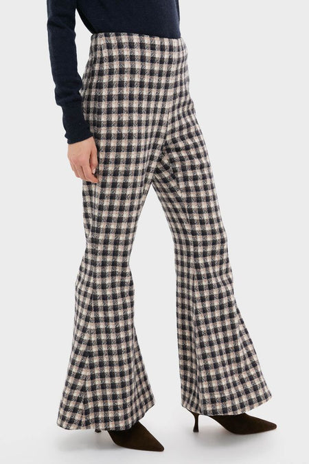 Model in Nude Trail Farah Dust Pant, high-waisted flared trousers with gingham plaid, styled with a dark top and kitten-heel boots, showcasing a classic, effortless, high-end look.