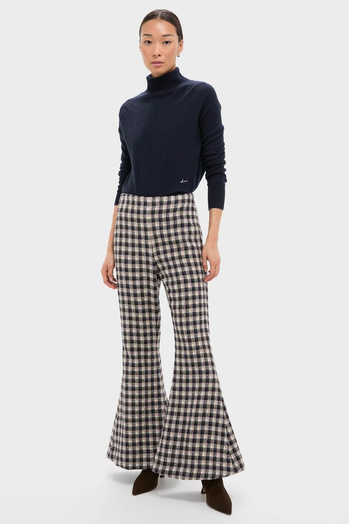 Model wearing Nude Trail Farah Dust Pant: classic gingham-check flared pants paired with a navy turtleneck, creating an effortless, high-end look with fun, confident style.