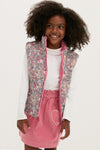 Young girl models a classic, effortless Floral Padded Gilet, featuring a reversible design with a zip-front, paired with a fun pink skirt for a high-end look.