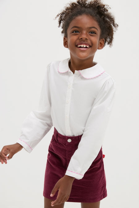 Young girl in Ric Rac Blouse showcasing a classic, high-end style with effortless charm, featuring pink ricrac-trimmed collar and cuffs, embodying fun sophistication.