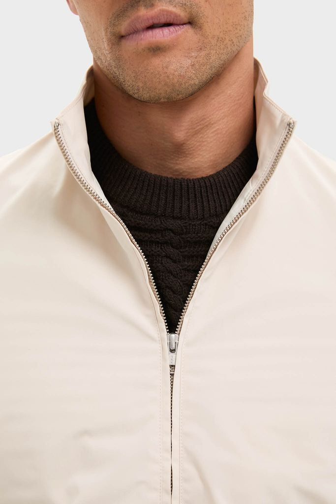 The Tan Stanley Jacket exudes classic sophistication with its suede-trimmed pockets and effortless style, layered over a dark cable-knit sweater for a high-end, modern look.