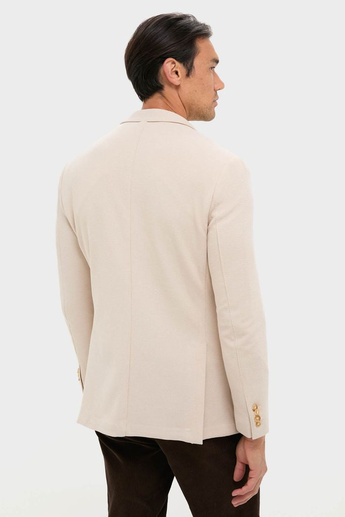 Effortlessly classic Tan Knit Travel Blazer on male model, showcasing its notch lapels and gold-tone cuffs, perfect for high-end travel and fun, confident style.