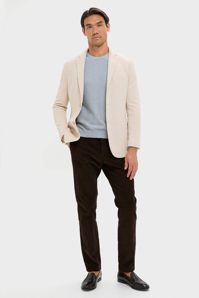 Model wearing the classic Tan Knit Travel Blazer, effortlessly styled with a crew-neck sweater and trousers, perfect for high-end travel or fun, confident office days.