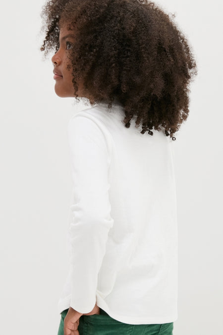 Young child in profile wearing Oso & Me's classic White Frank T-Neck, showcasing an effortless, high-end turtleneck style, ideal for layering and everyday fun.