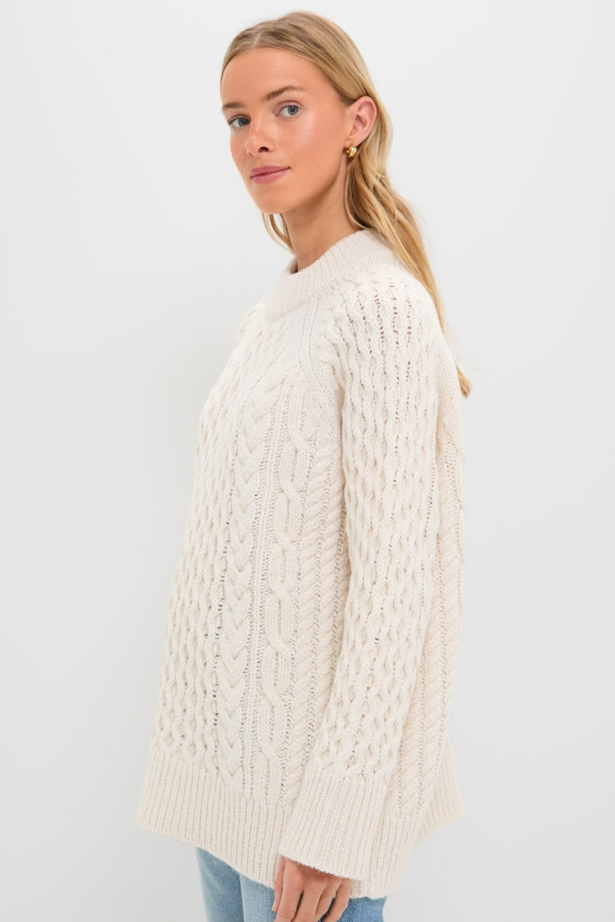 Ivory Galway Fisherman Sweater on woman, showcasing classic cable-knit design, relaxed fit, and ribbed trim for an effortlessly chic, high-end look. Perfectly pairs with jeans.