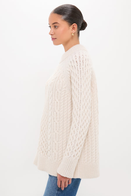 Woman in profile wearing the classic Ivory Galway Fisherman Sweater, showcasing its cable-knit design and relaxed fit for an effortlessly high-end, fun look with blue jeans.