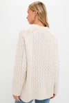 Person wearing the Ivory Galway Fisherman Sweater; a classic, cable-knit design with a relaxed fit, showcasing effortless, high-end style with ribbed collar, cuffs, and hem.
