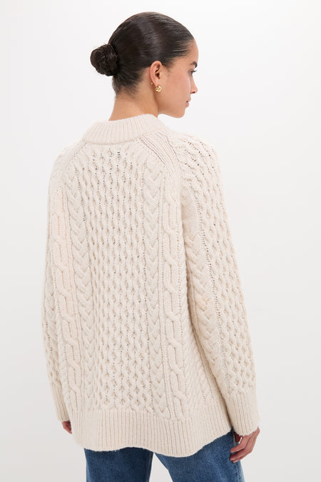 Model wearing the Ivory Galway Fisherman Sweater, showcasing its classic cable-knit texture and relaxed fit, paired effortlessly with jeans for a high-end, fun look.
