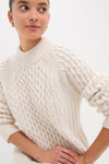 Ivory Galway Fisherman Sweater showcases classic cable-knit design, high ribbed neckline, and relaxed fit, embodying effortless, high-end style and fun, cozy comfort.
