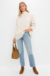 Model wearing the Ivory Galway Fisherman Sweater, showcasing its classic cable-knit design. Paired with jeans and boots, the look is effortlessly high-end and fun.