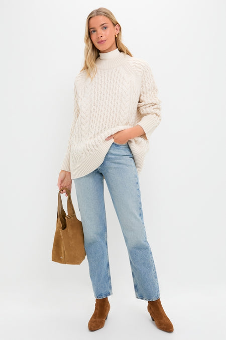 Model wearing the Ivory Galway Fisherman Sweater, showcasing its classic cable-knit design. Paired with jeans and boots, the look is effortlessly high-end and fun.