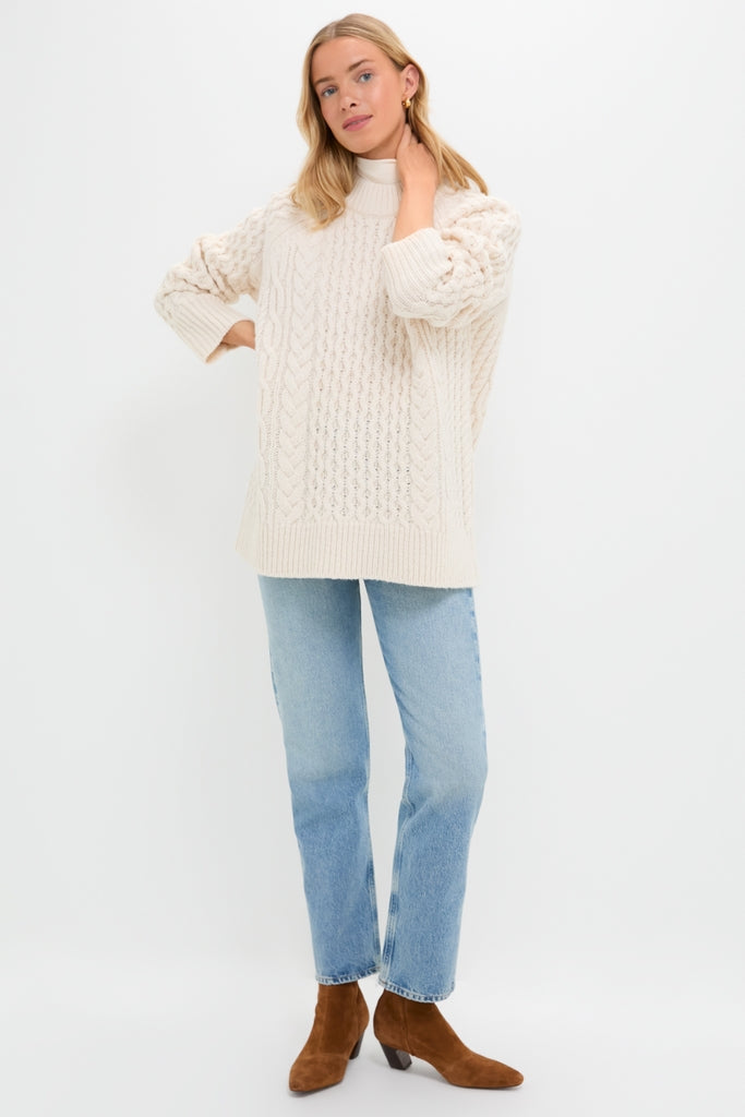 Model in Ivory Galway Fisherman Sweater with classic cable-knit, styled effortlessly with jeans and suede boots, embodying Tuckernuck's fun, high-end, and relaxed vibe.
