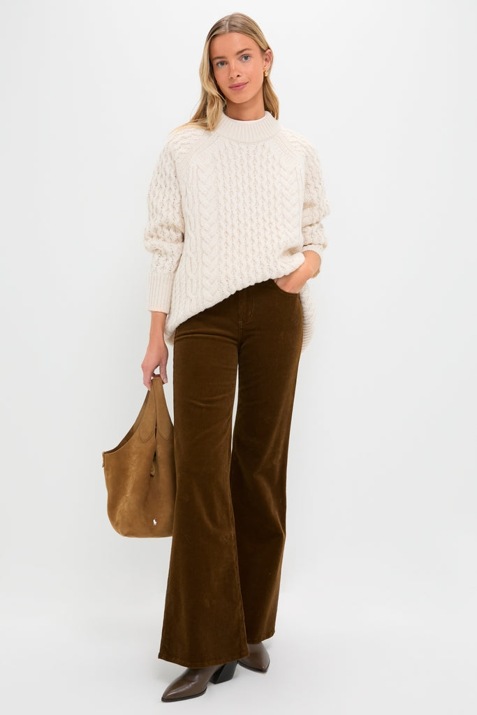 Woman wearing the Ivory Galway Fisherman Sweater, embodying classic, effortless style with a chunky knit, paired with flared trousers and a slouchy tote, exuding high-end, fun fashion.