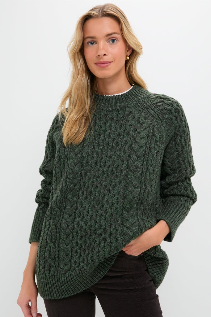 Model wearing the Hunter Green Galway Fisherman Sweater, showcasing classic cable-knit design and relaxed fit, embodying effortless, high-end style with a fun, modern twist.