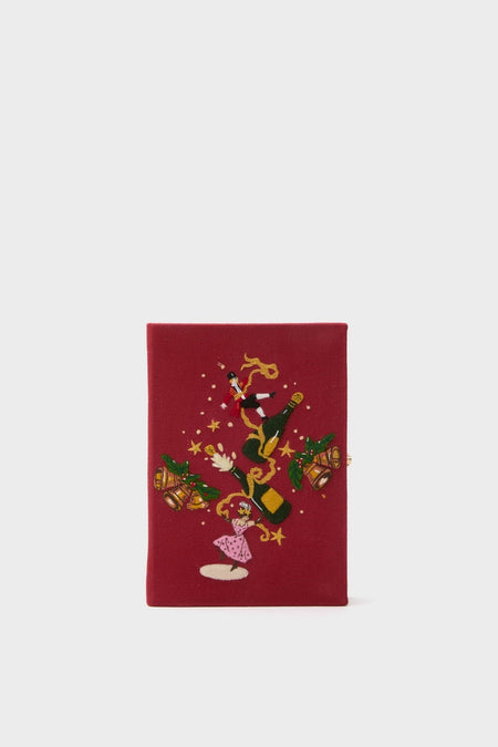 Camelia Holly Jingle and Mingle Book Clutch: A classic, hand-embroidered, festive clutch featuring a champagne scene, blending effortless fun with high-end elegance for book lovers.