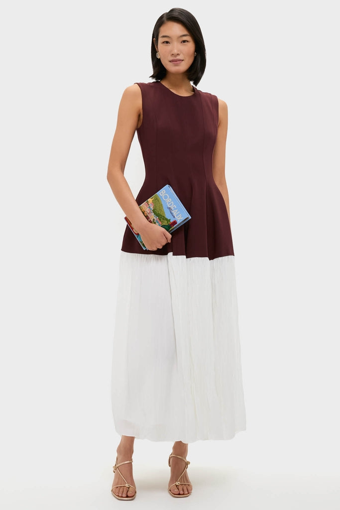 Model holds the Hortensia Bordeaux Book Clutch, a classic, high-end, hand-embroidered accessory, exuding effortless elegance and fun against a light backdrop.