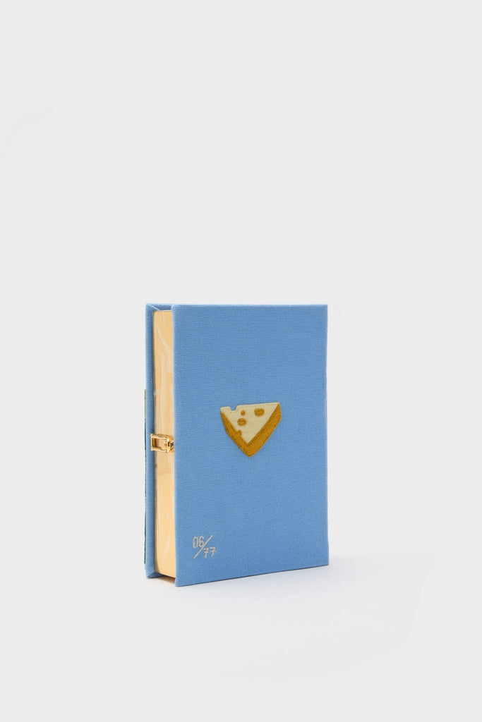Hortensia Bordeaux Book Clutch, a high-end, classic accessory featuring a light-blue fabric with cheese appliqué and gold clasp, effortlessly blending fun and elegance.