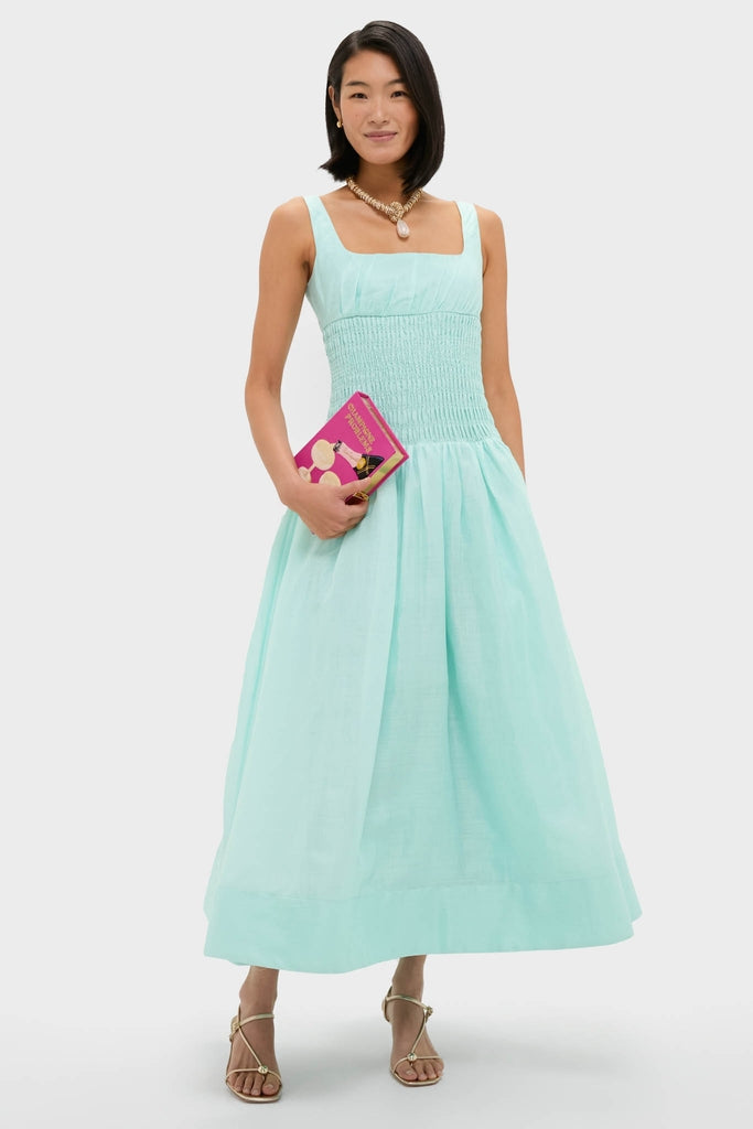 Young woman in a mint-green dress holding the Fuchsia Champagne Problems Book Clutch, a classic, high-end, hand-embroidered accessory, adding effortless fun to her stylish ensemble.