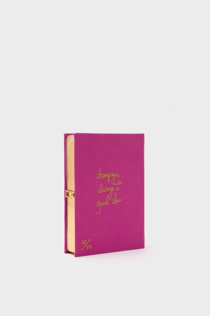 Fuchsia Champagne Problems Book Clutch: a classic, high-end accessory with fuchsia fabric, gold script, and a numbered edition, blending effortless fun and elegance for book lovers.