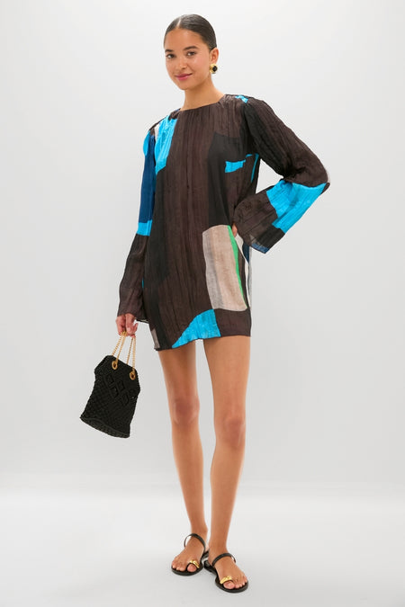 Woman showcasing the classic Black Kibera Sandals, featuring gold-accented toe straps for an effortless, high-end look. Paired with a tunic dress and woven handbag for fun styling.