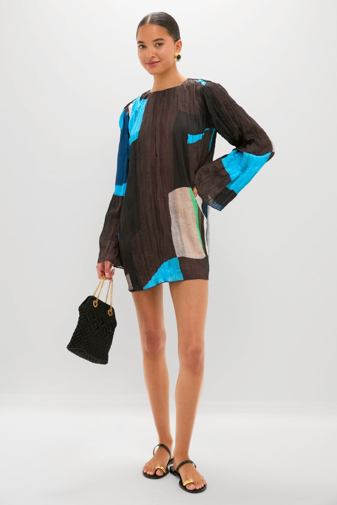 Woman showcasing the classic Black Kibera Sandals, featuring gold-accented toe straps for an effortless, high-end look. Paired with a tunic dress and woven handbag for fun styling.