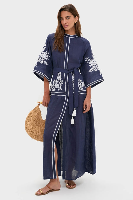 Cognac Kibera Sandals: Classic, effortless brown slide sandals with a gold-toned toe ring and arch strap, perfectly paired with a navy dress for a high-end, fun look.