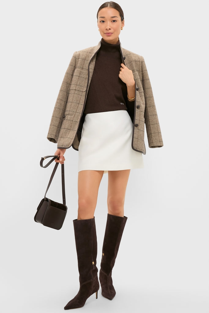 Woman styled in a classic, high-end look with the Cream Wool Meg Mini Skirt, creating an effortless, fun ensemble with dark hues and minimal accessories.