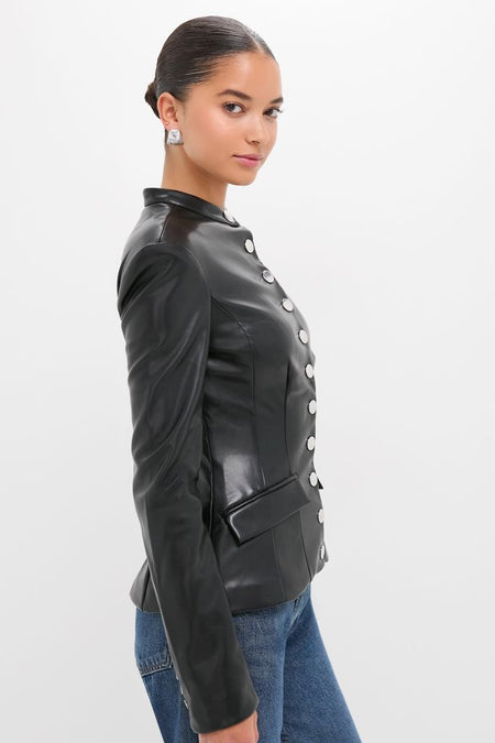 Young woman in profile wearing a Black Vegan Leather Military Jacket with silver buttons, flap pockets, and a tailored fit, paired with blue jeans and a sculptural silver earring.