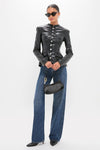 Model wearing the classic Black Vegan Leather Military Jacket with large silver buttons, paired with high-waisted jeans and kitten heels, exuding an effortless, high-end style.