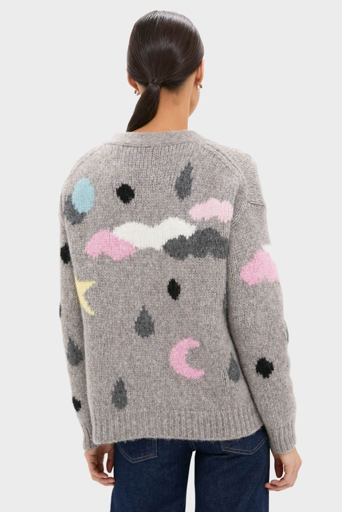 Person in a classic, high-end Grey Weather Cycles Intarsia Stormy Cardigan, featuring whimsical weather motifs, paired with dark jeans for an effortlessly fun, relaxed look.